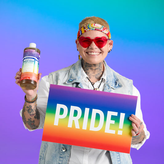 Person holding a bottle of soap and a rainbow-colored 'PRIDE!' sign against a colorful gradient background [946mL]